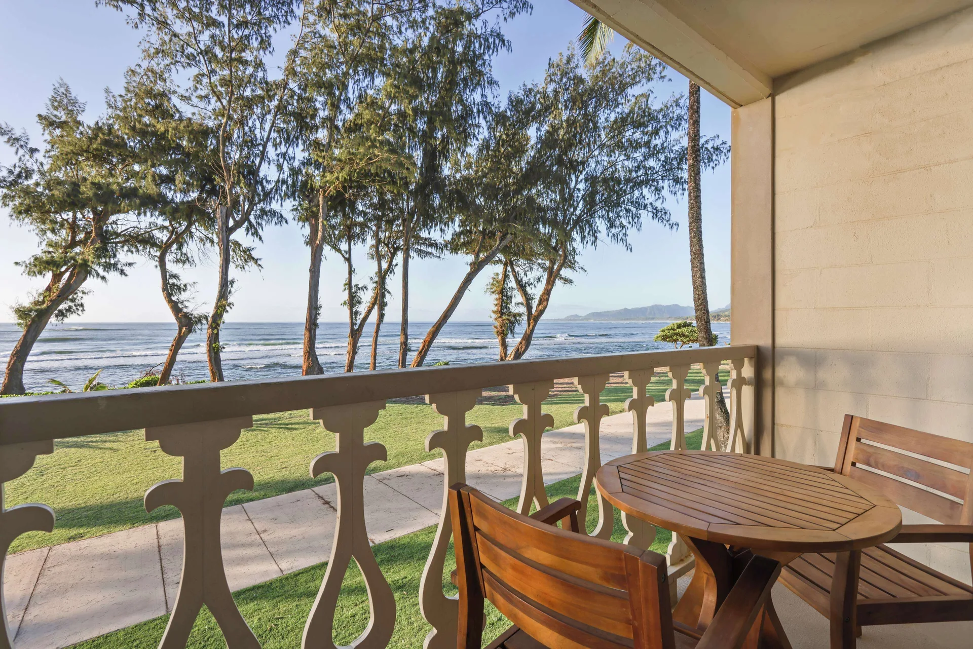Oceanfront balcony with wooden table and chairs overlooking the shoreline at Aston Islander on the Beach.