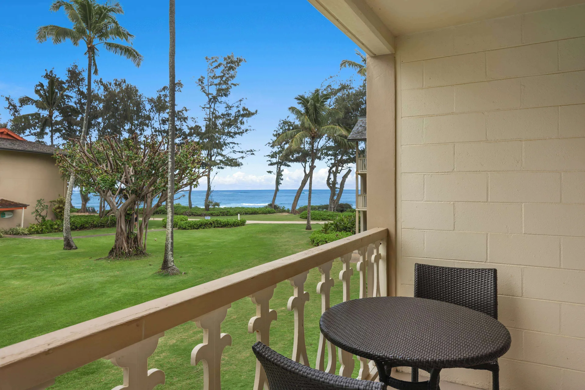 Balcony seating with lawn, palms, and partial ocean view at Aston Islander on the Beach.