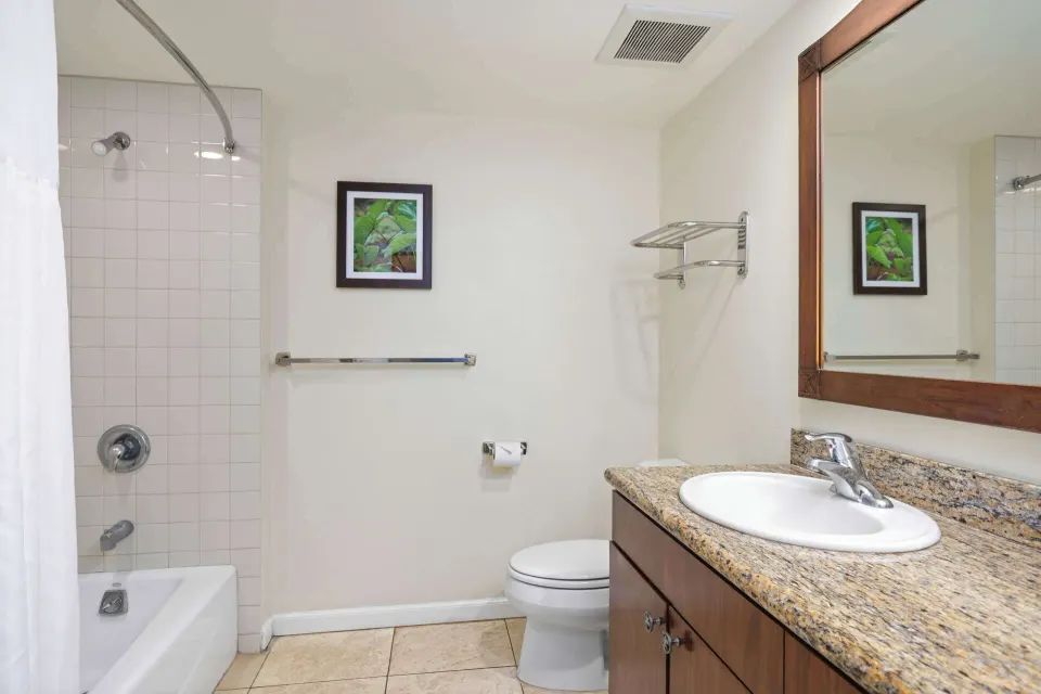 Bathroom with vanity, mirror, toilet, and tub shower at Aston Islander on the Beach.