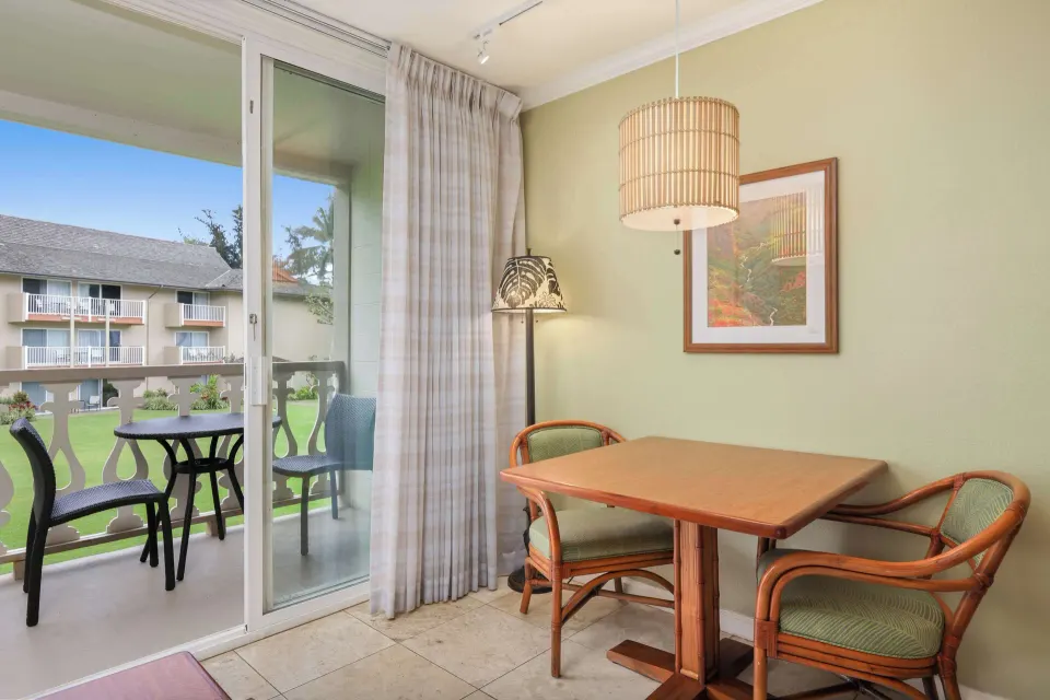 Dining table beside balcony doors in a partial ocean view room at Aston Islander on the Beach.