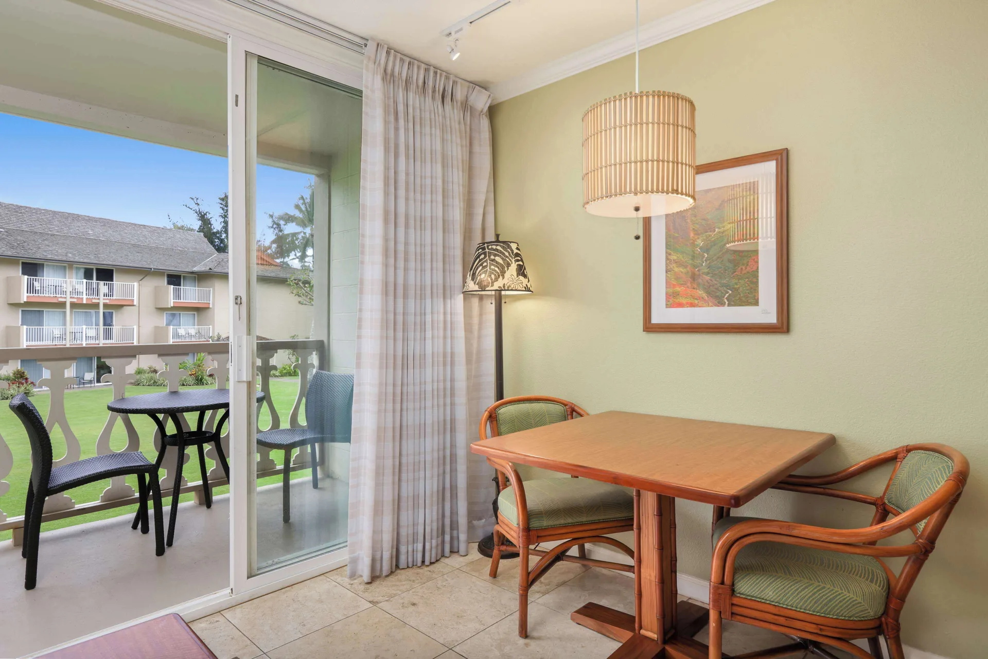 Dining table beside balcony doors in a partial ocean view room at Aston Islander on the Beach.