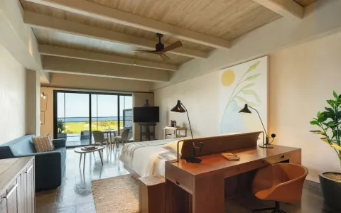 King bed guest room with sofa and large windows at Atelier Playa Mujeres.