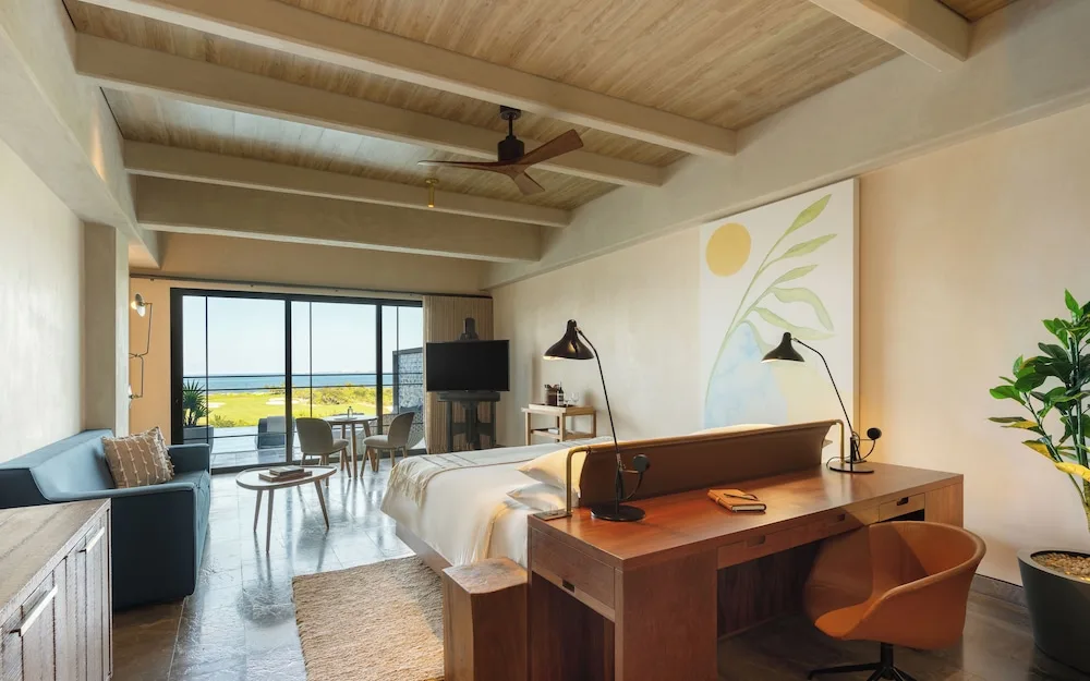 King bed guest room with sofa and large windows at Atelier Playa Mujeres.