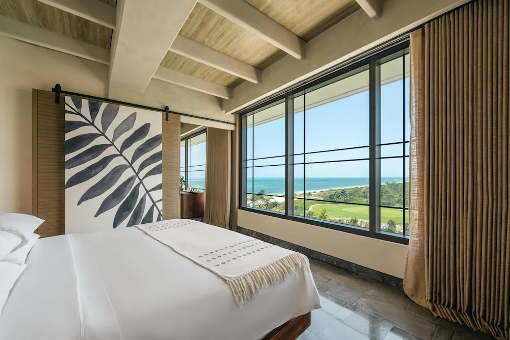 Ocean-view king bed guest room with large windows at Atelier Playa Mujeres.