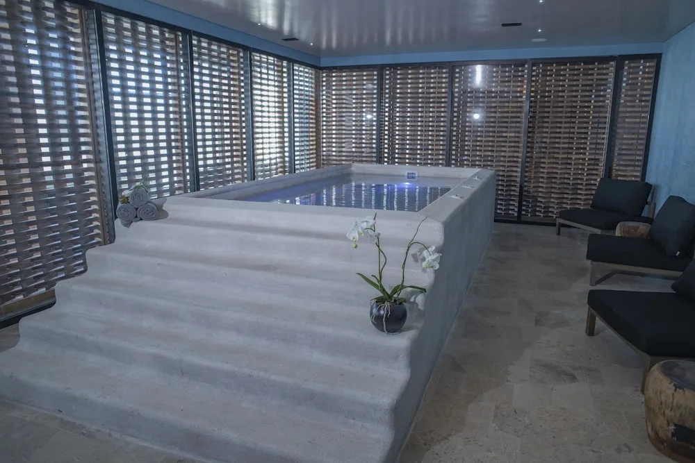 Spa hydrotherapy pool with lounge chairs and wood screens at Atelier Playa Mujeres.