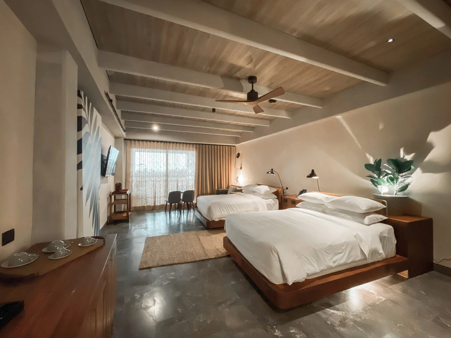 Inspira Corner Suite bedroom with two beds and wood-beam ceiling at Atelier Playa Mujeres.