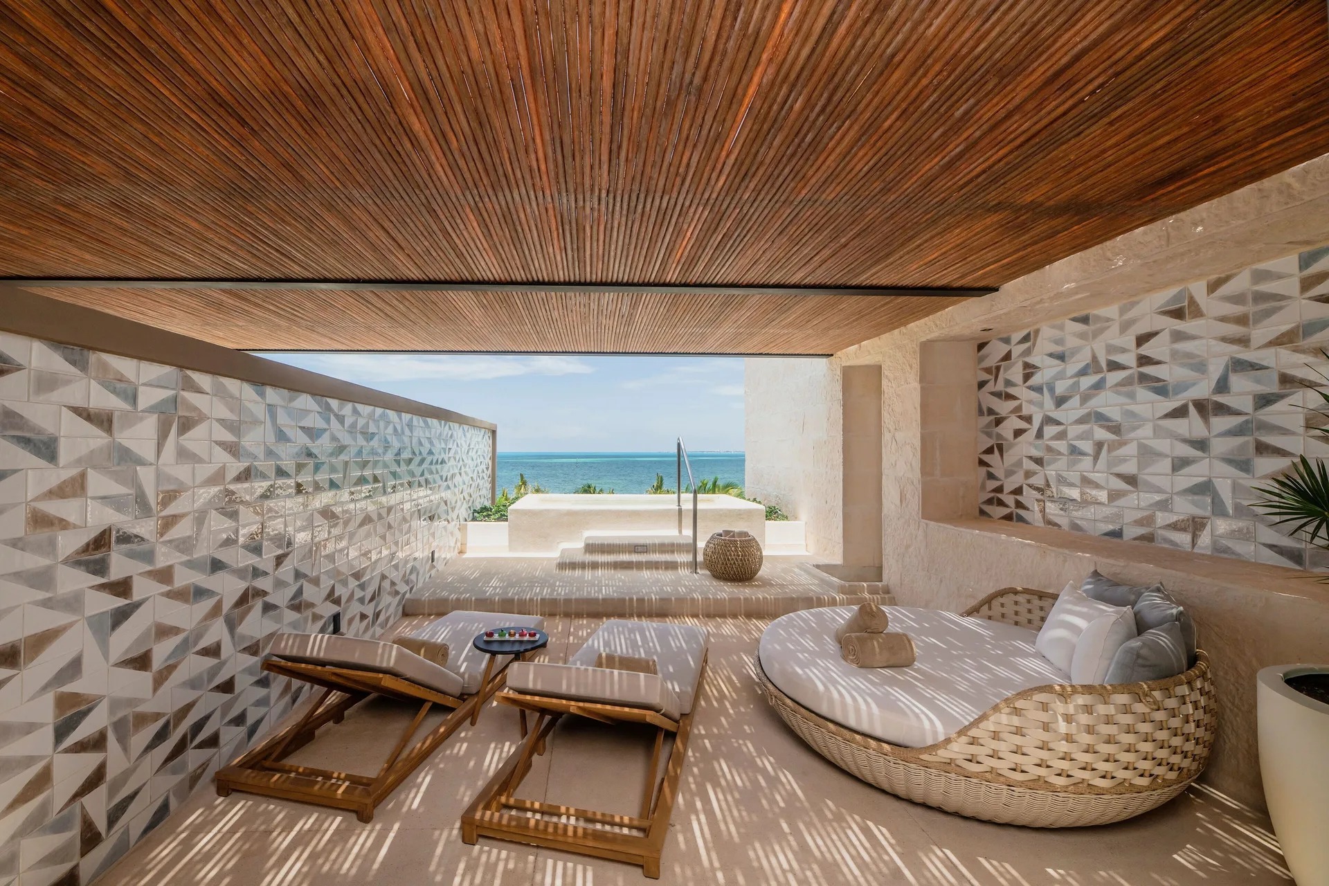 Oceanfront terrace with loungers and daybed at Atelier Playa Mujeres.