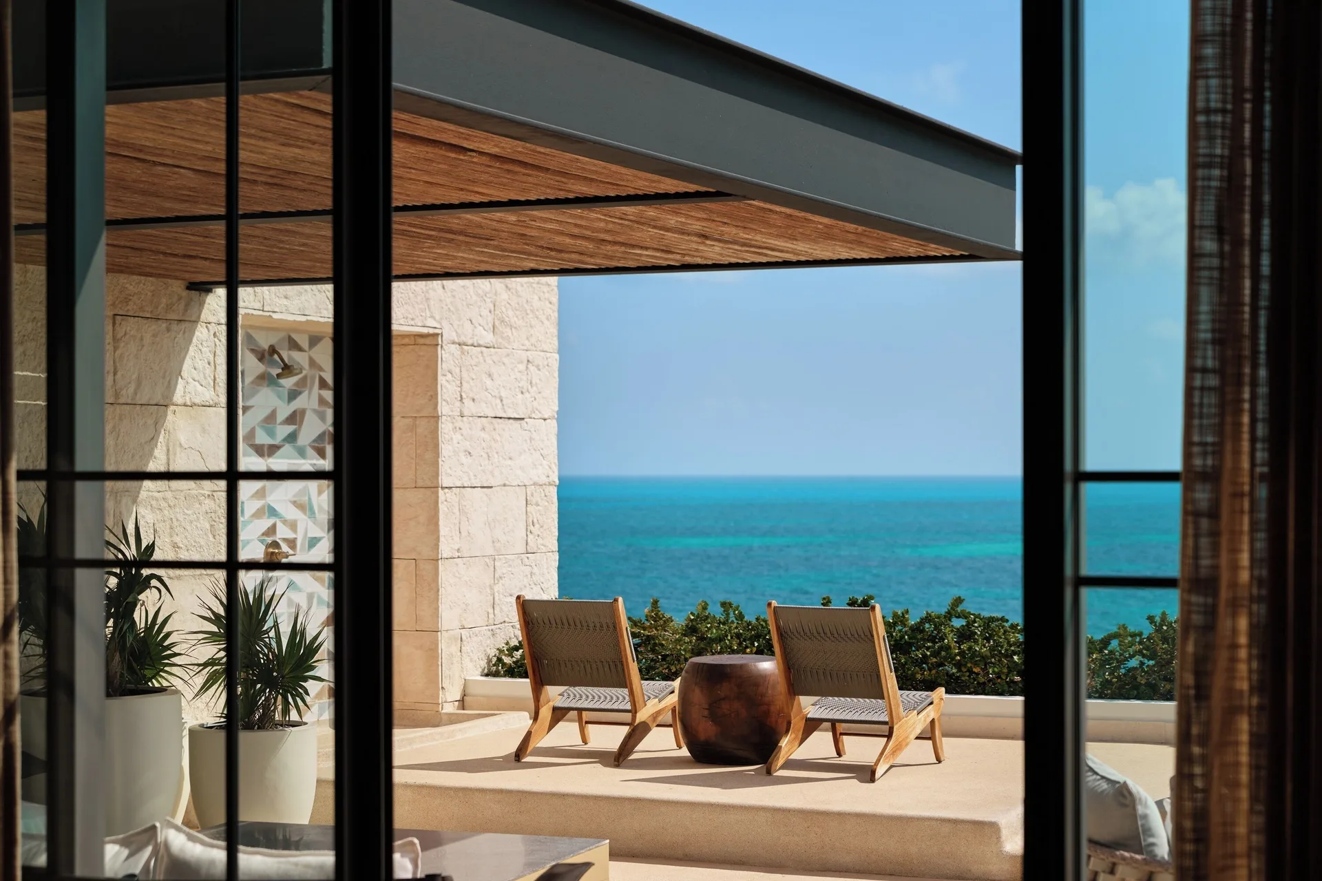 Inspira Master Suite Ocean Front terrace chairs seen through glass at Atelier Playa Mujeres.