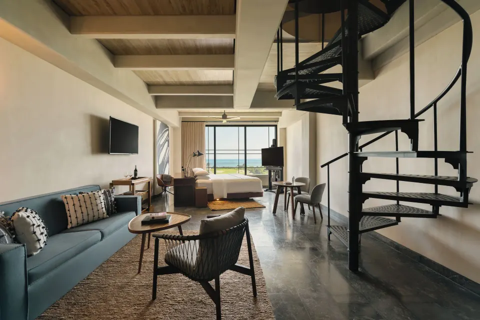 Inspira Rooftop Suite with bed, sofa, spiral staircase and ocean view at Atelier Playa Mujeres.