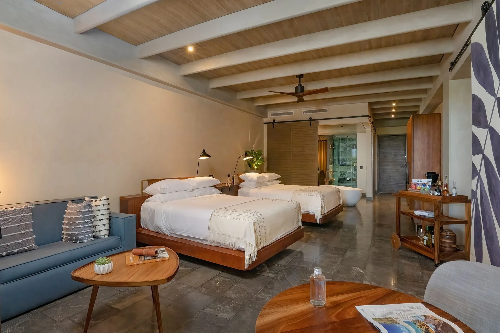 Inspira Terrace Suite with two beds, sofa, and open bath at Atelier Playa Mujeres.