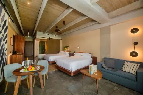 Junior Suite with two beds, sofa, dining table, and soaking tub at Atelier Playa Mujeres.