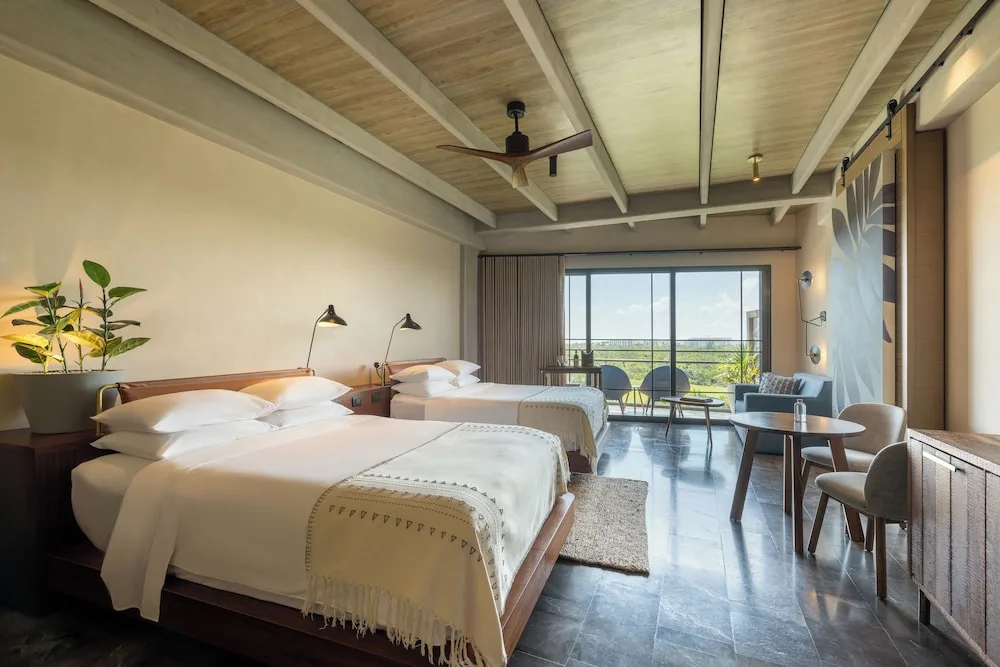 Two beds and seating area in a Junior Suite Ocean View at Atelier Playa Mujeres.