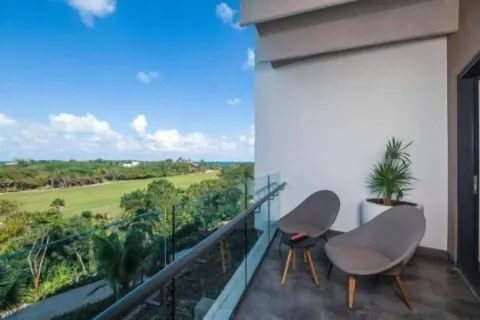 Junior Suite balcony with two chairs and distant sea view at Atelier Playa Mujeres.