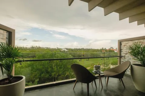 Junior Suite balcony with chairs and green view at Atelier Playa Mujeres.