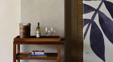 Junior Suite bar cart with wine bottle, glasses, and wall art at Atelier Playa Mujeres.