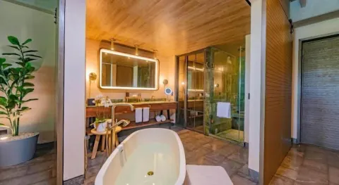Junior Suite bathroom with freestanding tub, vanity, shower, and hallway at Atelier Playa Mujeres.