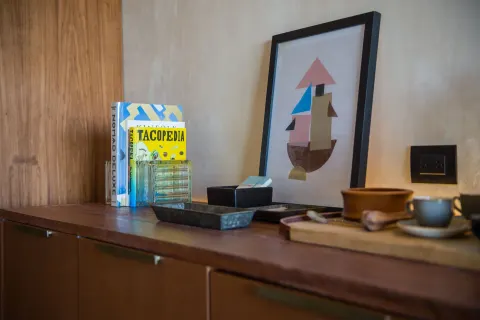 Junior Suite cabinet with books, framed art and coffee items at Atelier Playa Mujeres.