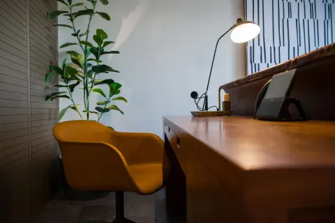 Junior Suite desk with mustard chair and plant at Atelier Playa Mujeres.