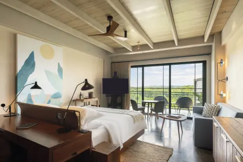 Junior Suite king bed with balcony and sitting area at Atelier Playa Mujeres.