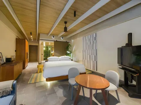 Junior Suite king bed and seating area inside Atelier Playa Mujeres.