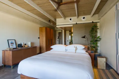 Junior Suite king bed with wood furnishings at Atelier Playa Mujeres.