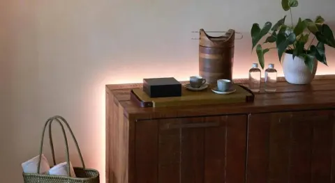 Junior Suite wood cabinet with cups, bottles, plant, and basket at Atelier Playa Mujeres.