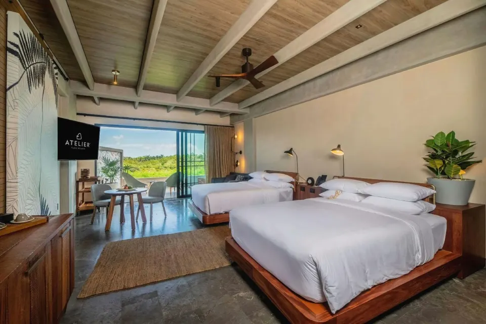 Junior Suite with two beds and balcony doors at Atelier Playa Mujeres.