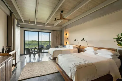 Junior Suite with two beds and balcony seating at Atelier Playa Mujeres.