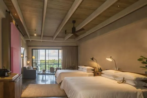 Junior Suite with two beds, sofa, and balcony doors at Atelier Playa Mujeres.