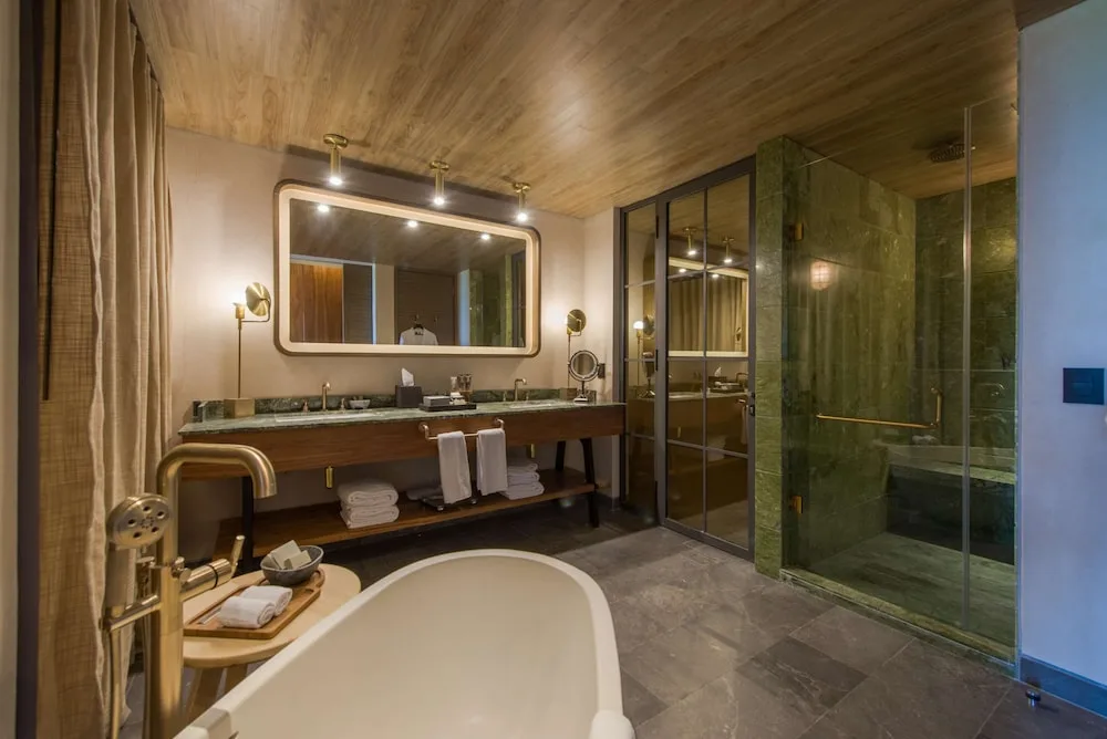 Accessible junior suite bath with freestanding tub and glass shower at Atelier Playa Mujeres.