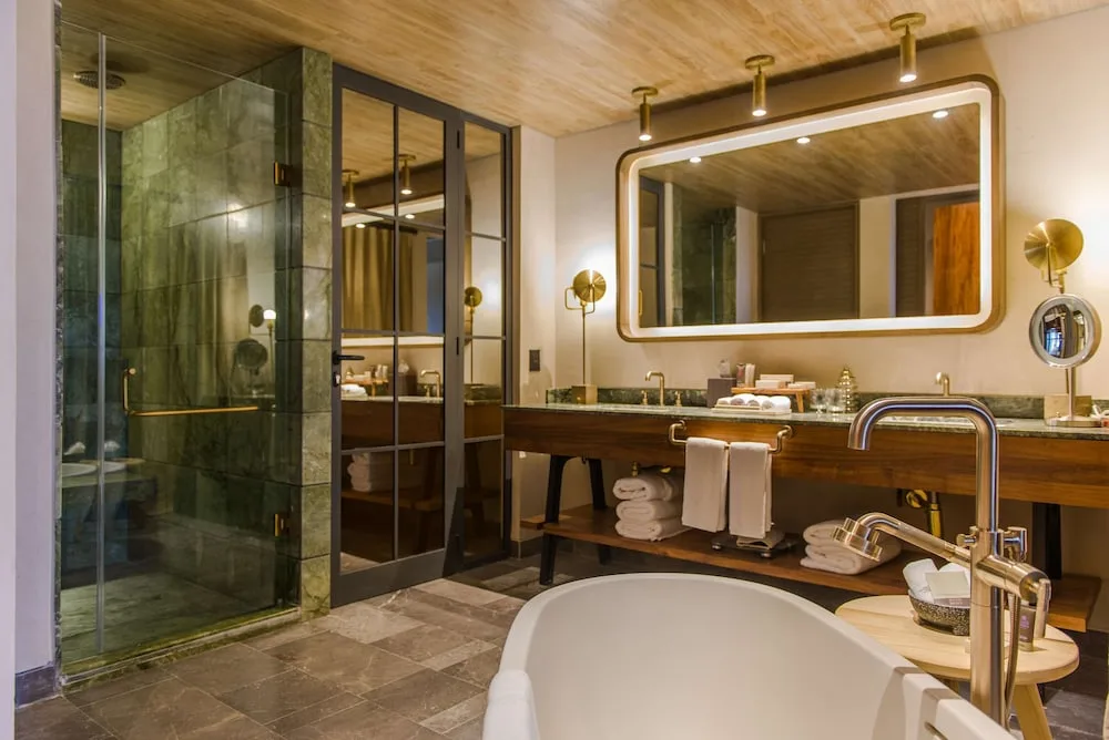 Accessible junior suite bathroom with tub and shower at Atelier Playa Mujeres.