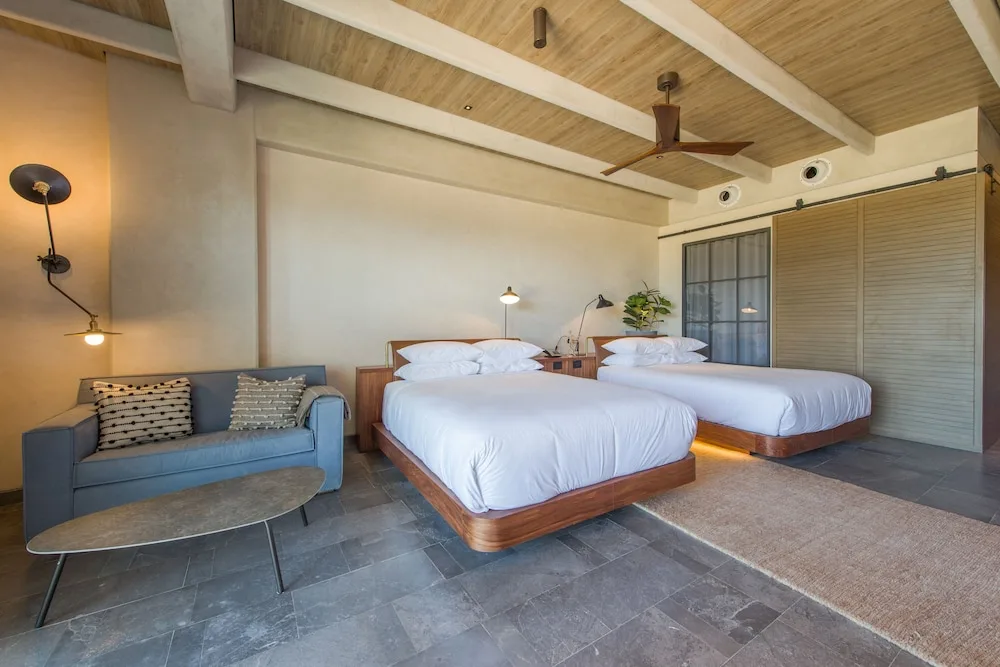 Two beds and blue sofa in a Wheelchair Accessible Junior Suite at Atelier Playa Mujeres.