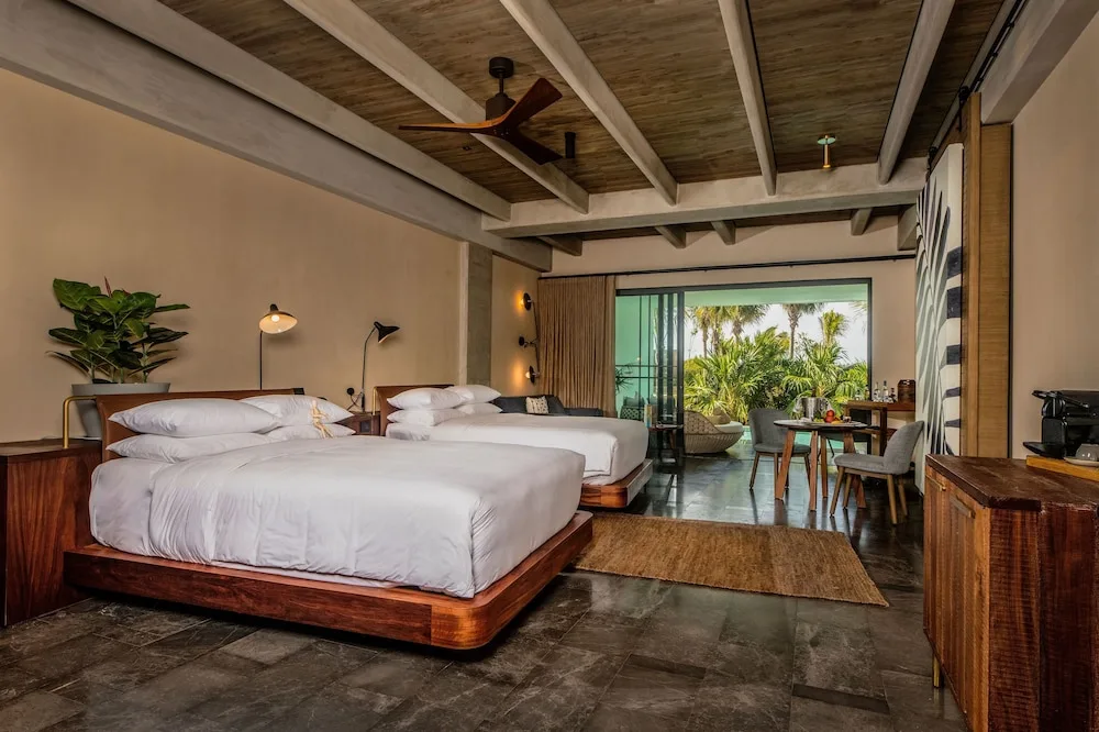 Two beds and terrace seating in a Wheelchair Accessible Junior Suite at Atelier Playa Mujeres.