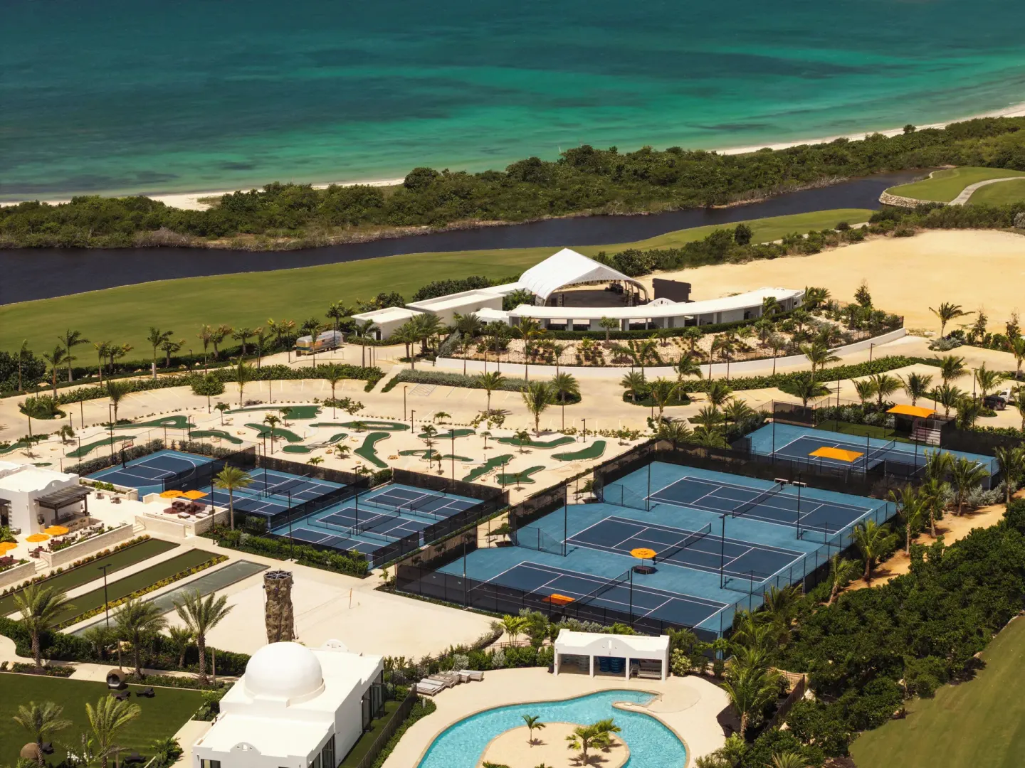 Aerial view of tennis courts, pool, and shoreline at Aurora Anguilla Resort & Golf Club.