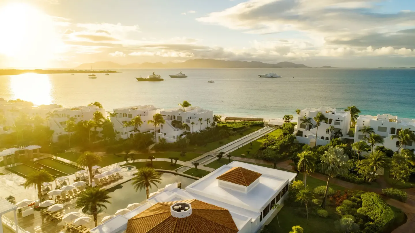 Aerial sunset view of beachfront buildings and sea at Aurora Anguilla Resort & Golf Club.