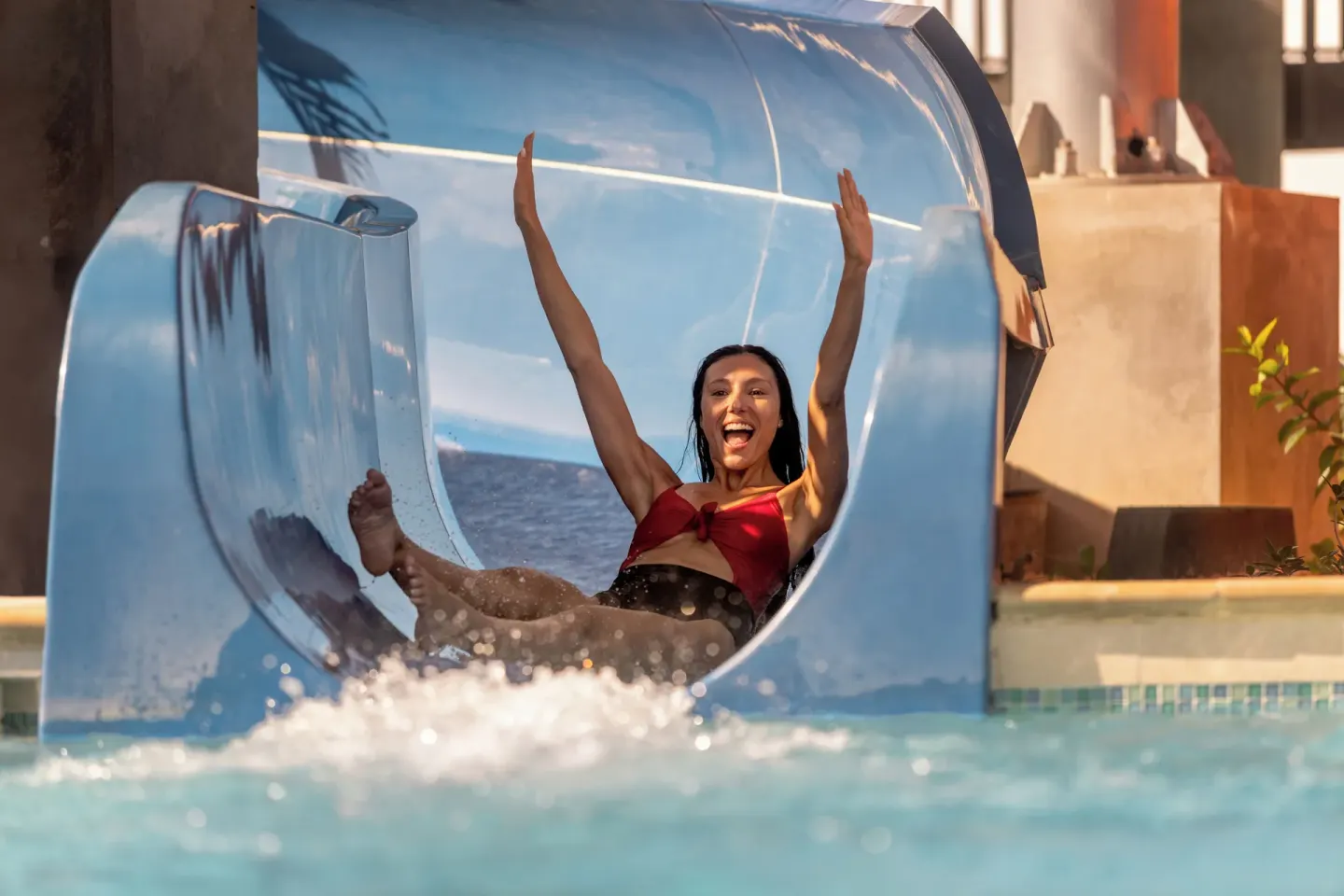 A guest exits a blue waterslide into the pool at Aurora Anguilla Resort & Golf Club.