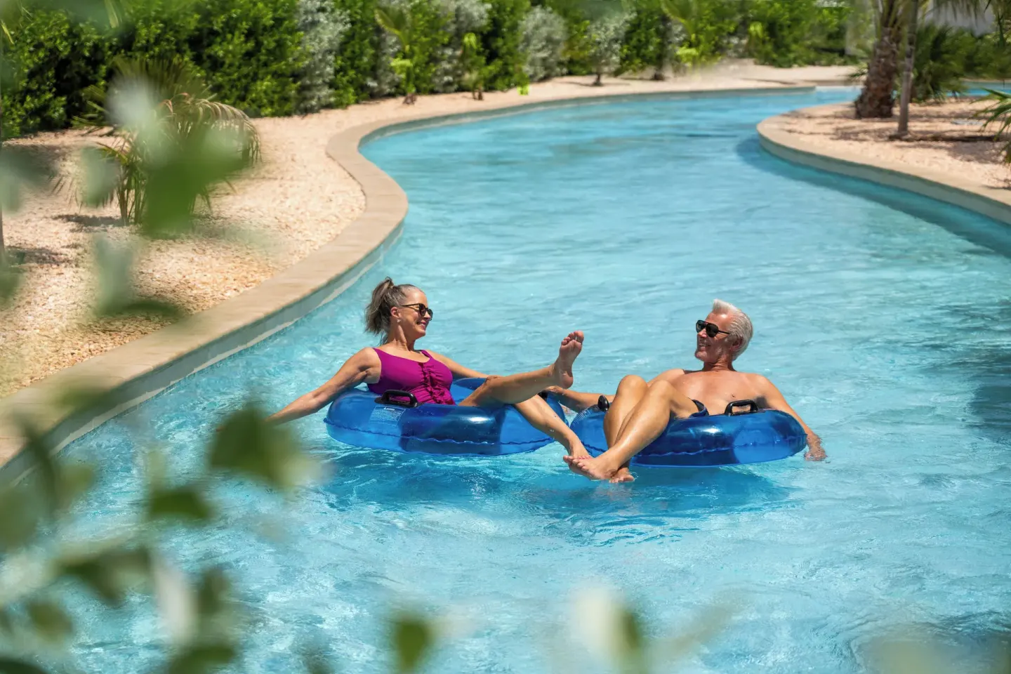 Two guests float in blue tubes on a lazy river at Aurora Anguilla Resort & Golf Club.