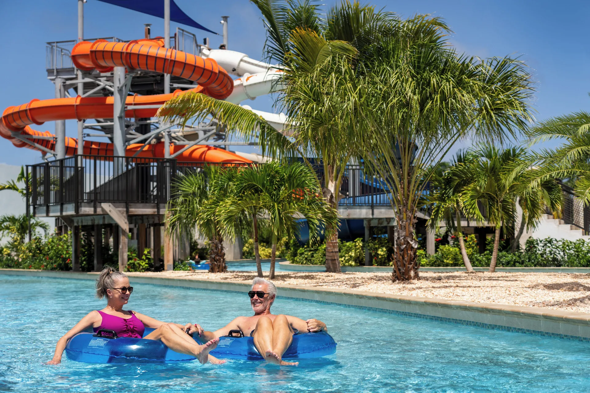 Guests float on a lazy river below orange waterslides at Aurora Anguilla Resort & Golf Club.
