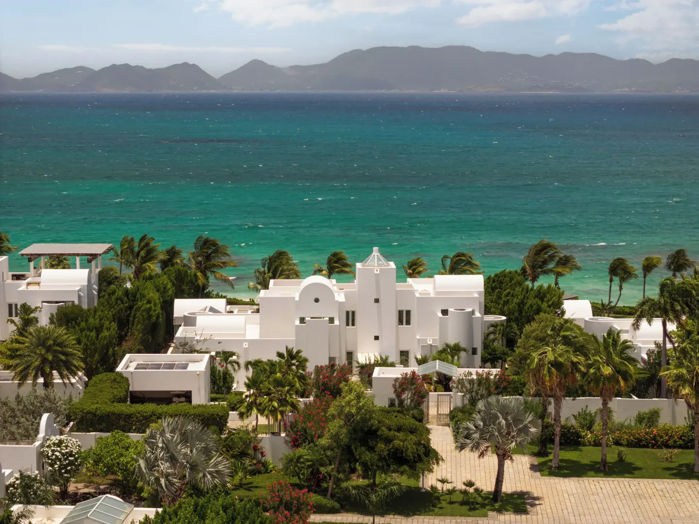 White resort buildings and gardens overlook turquoise sea at Aurora Anguilla Resort & Golf Club.