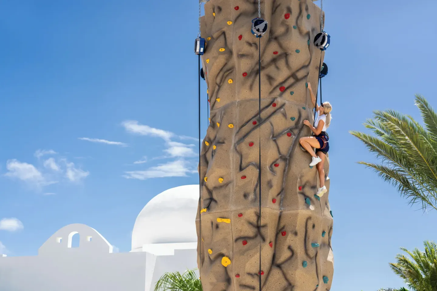 A climber scales an outdoor rock wall at Aurora Anguilla Resort & Golf Club.