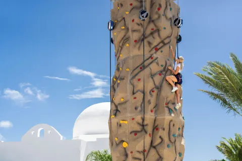 A climber scales an outdoor rock wall at Aurora Anguilla Resort & Golf Club.