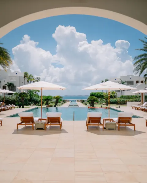 Pool courtyard with umbrellas and ocean beyond at Aurora Anguilla Resort & Golf Club.
