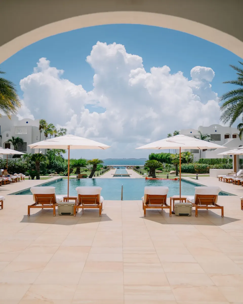 Pool courtyard with umbrellas and ocean beyond at Aurora Anguilla Resort & Golf Club.