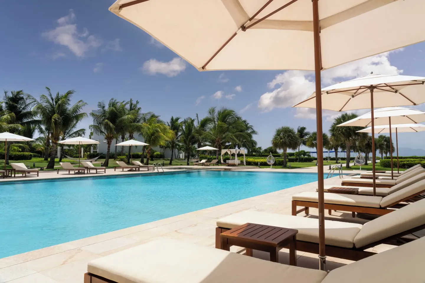 Pool loungers and white umbrellas line the water at Aurora Anguilla Resort & Golf Club.