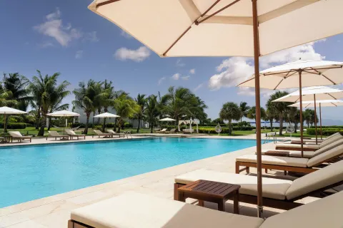 Pool loungers and white umbrellas line the water at Aurora Anguilla Resort & Golf Club.