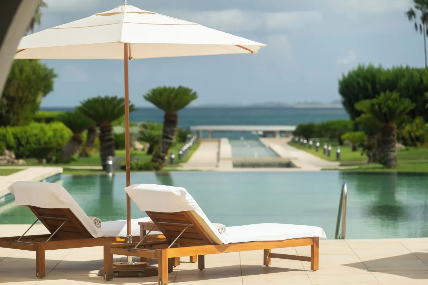 Poolside loungers and umbrella face the sea at Aurora Anguilla Resort & Golf Club.
