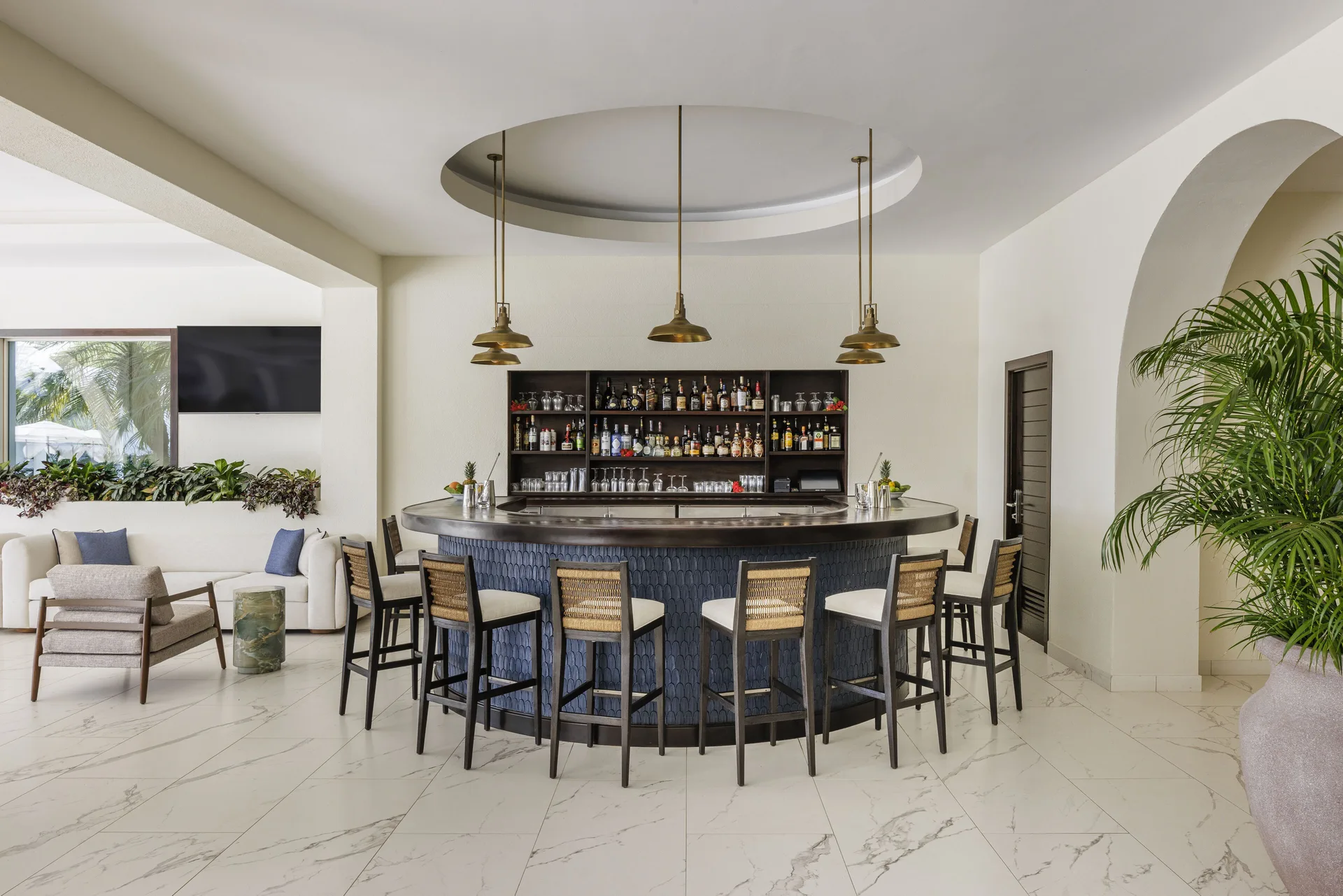 Curved bar with high stools and pendant lights at Aurora Anguilla Resort & Golf Club.