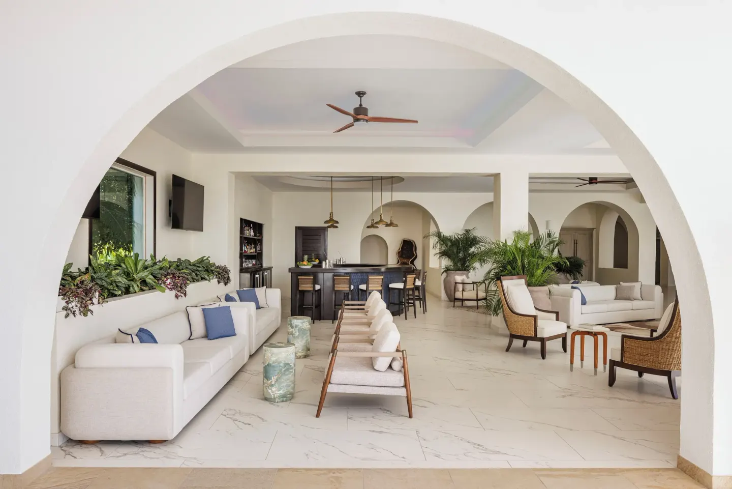Open lounge with sofas, arched openings, and a bar at Aurora Anguilla Resort & Golf Club.
