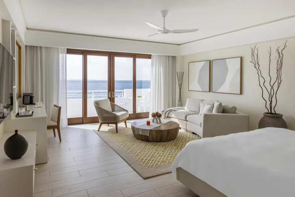 Beachfront Junior Suite with bed, sitting area, and ocean-facing balcony at Aurora Anguilla Resort & Golf Club.