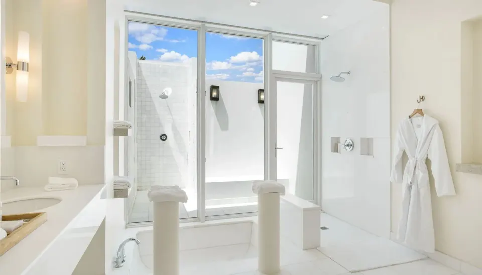 Bright villa bathroom with tub, shower, and robe at Aurora Anguilla Resort & Golf Club.